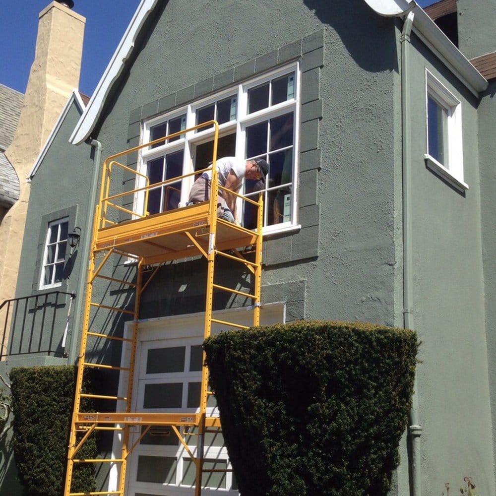 Crew installing windows from scaffolding on a stucco home