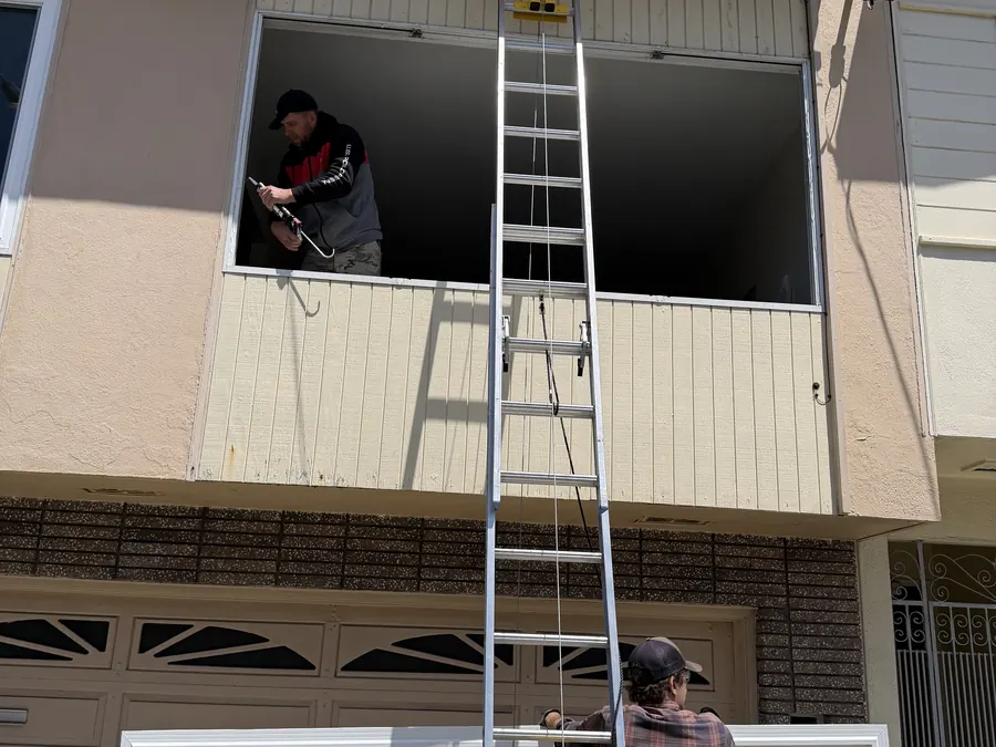 Window Station installers setting a new window from a ladder, South San Francisco, CA