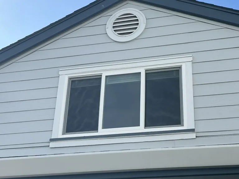 Three-panel white slider in a gable end below a round vent, Foster City, CA