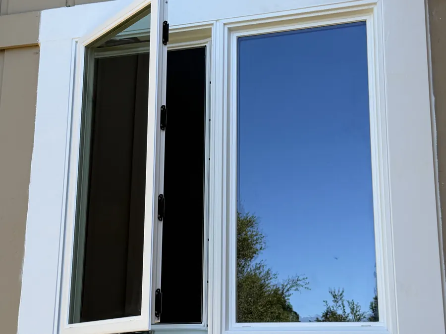 Newly installed casement window swung open, with wide white trim, San Carlos, CA